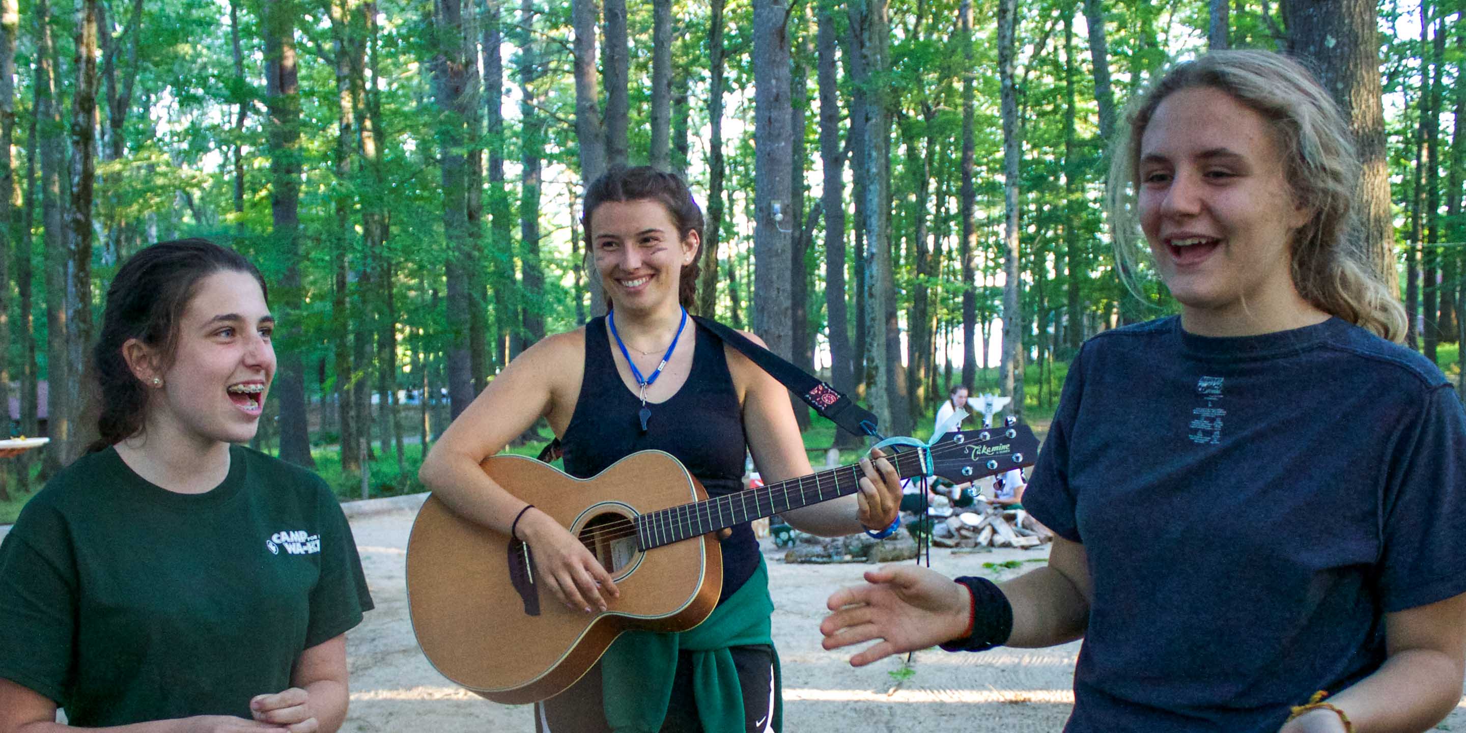 Staff playing guitar and campers singing