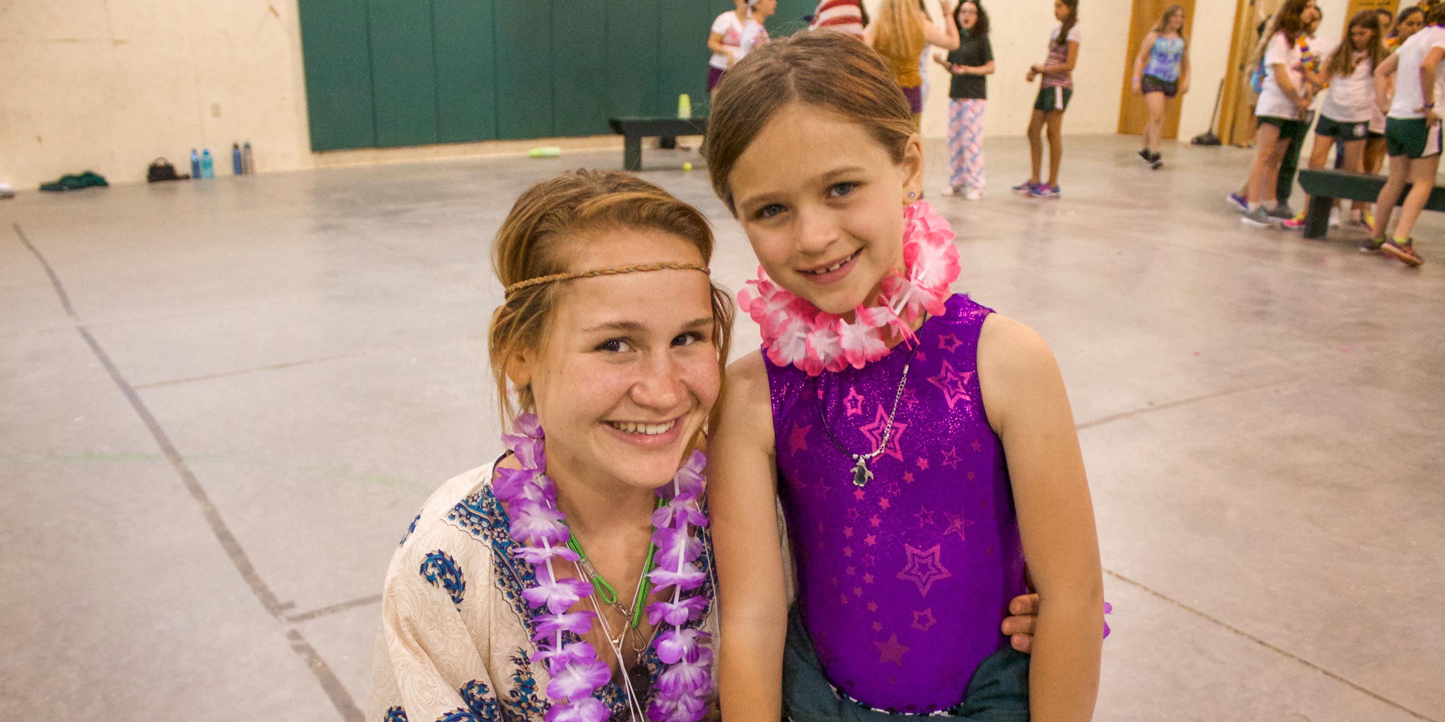 Staff with young camper dressed in Hawaiian leis