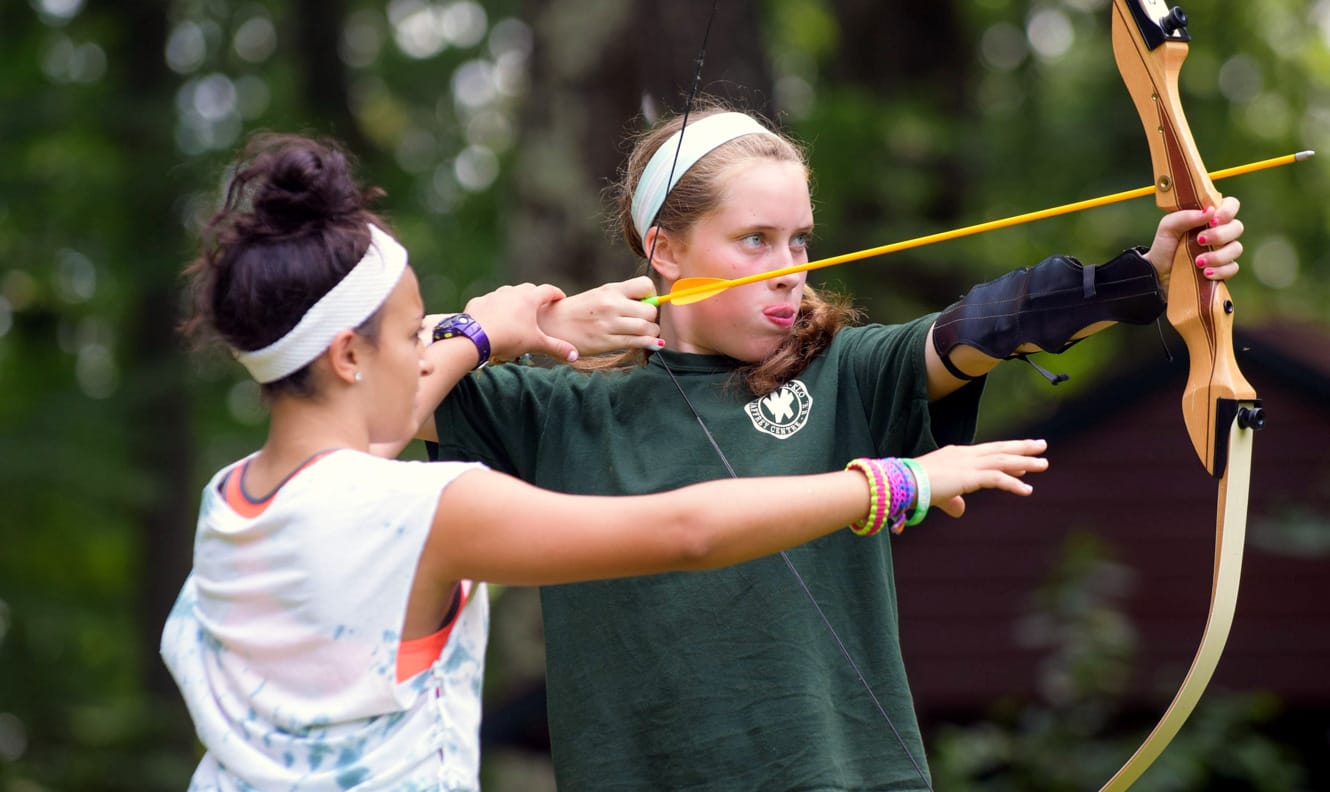 Staff helping camper at archery