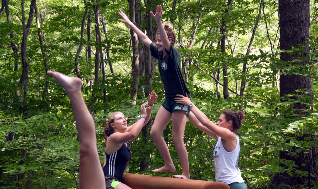 Staff helping camper on balance beam