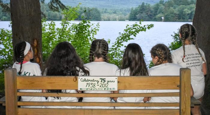 Girls sitting on a bench looking out at lake