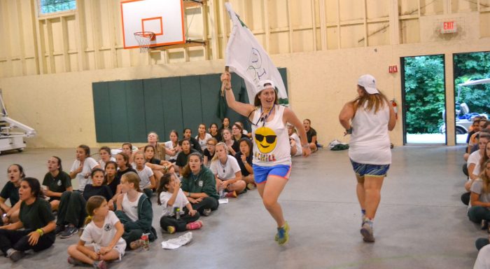 Staff running through assembly with a flag