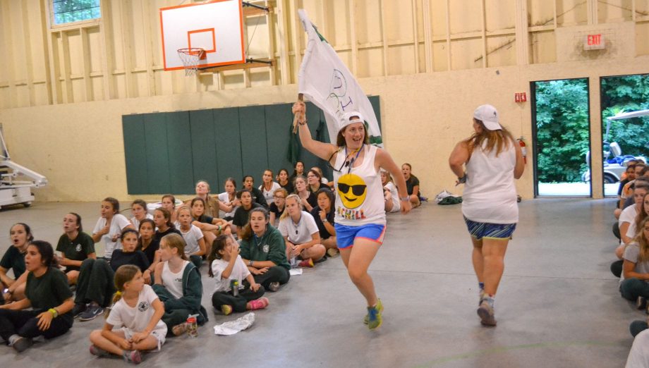 Staff running through assembly with a flag