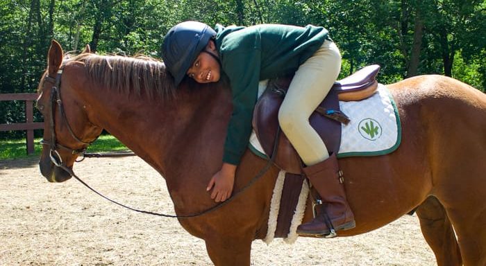 Girl horseback riding and hugging horse