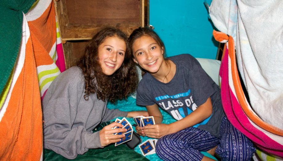 Two girls playing cards in their bunk
